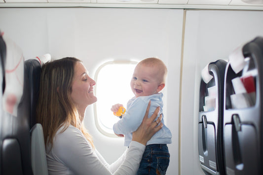 Une maman tenant son bébé dans les bras à bord d’un avion