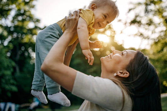 une maman porte son enfant dans ses bras et sont tous les deux souriants